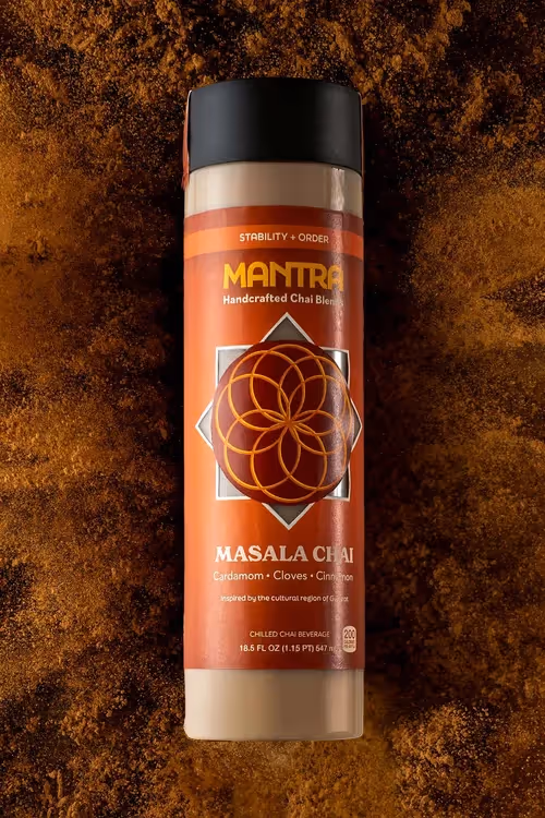 MANTRA Masala Chai stick pack standing in cocoa powder on dark backdrop, product photography by Photos by Lars.