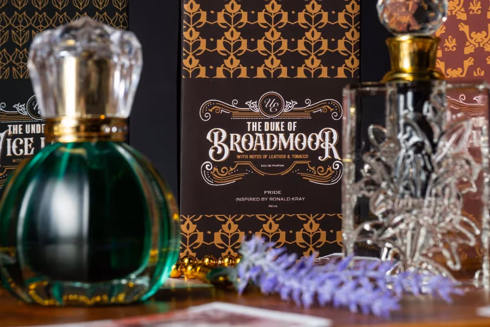 Green glass bottle with ice cubes beside Broadmoor packaging on a patterned set, product photography by Photos by Lars.