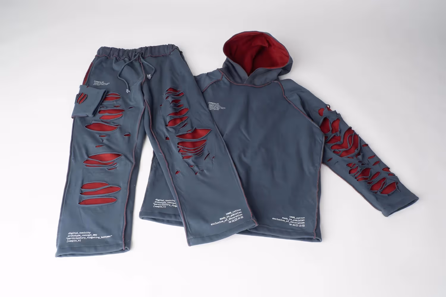 Blue hoodie and sweatpants set with red graphic accents laid flat on white, apparel photography by Photos by Lars.