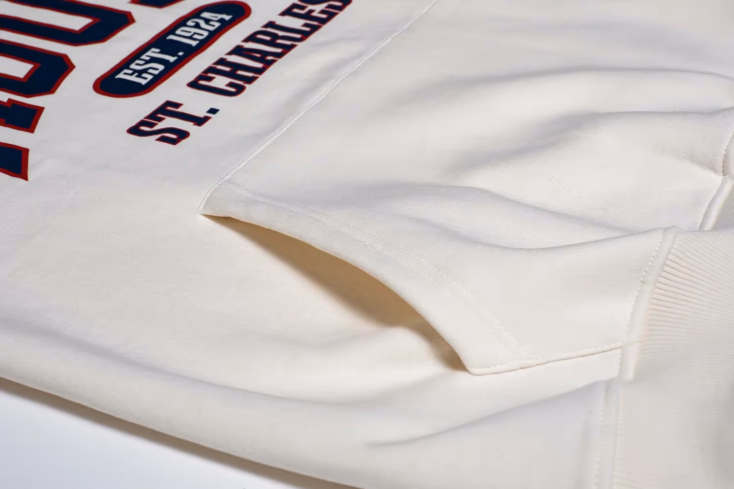Folded white sweatshirt sleeve showing printed text “St. Charles” in red and navy, apparel photography by Photos by Lars.