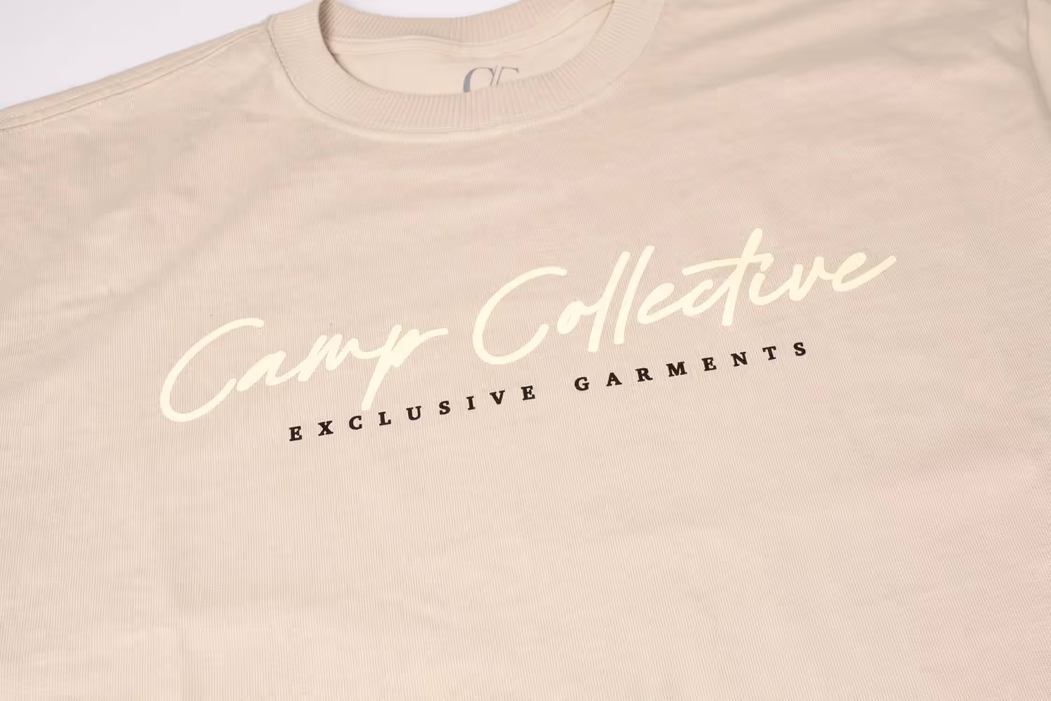 Beige shirt close-up showing Camp Collective script logo, apparel product photography by Photos by Lars.