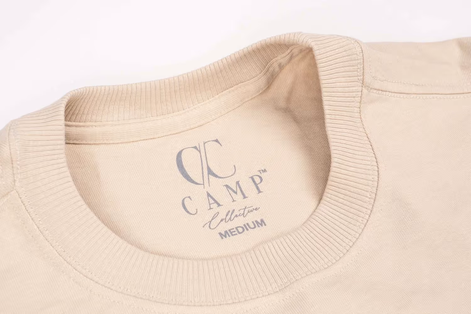 Close-up of CC Camp Collective neck label inside beige tee, product detail photography by Photos by Lars.