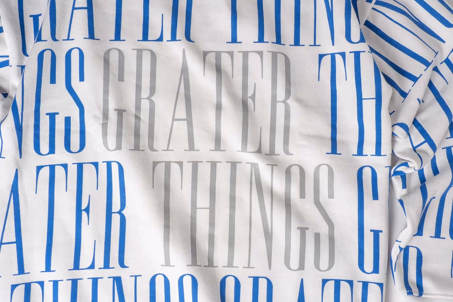 Close-up of blue 'GREATER THINGS' print on striped fabric, apparel detail photography by Photos by Lars.