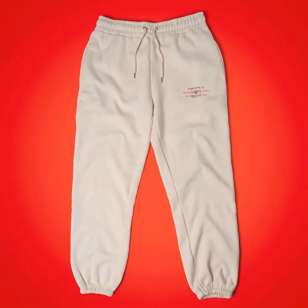 Cream Grater Things sweatpants laid flat on red background, product photography by Photos by Lars.