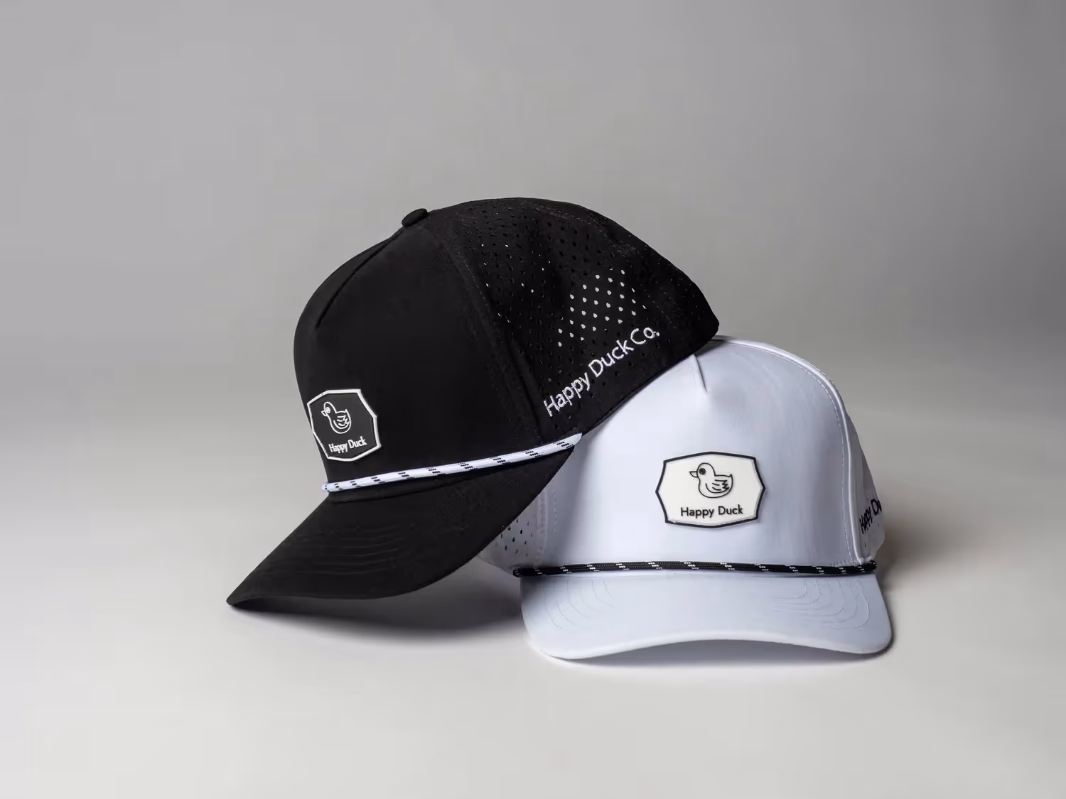 Black and white trucker caps stacked with logo patch on front, ecommerce photography by Photos by Lars.