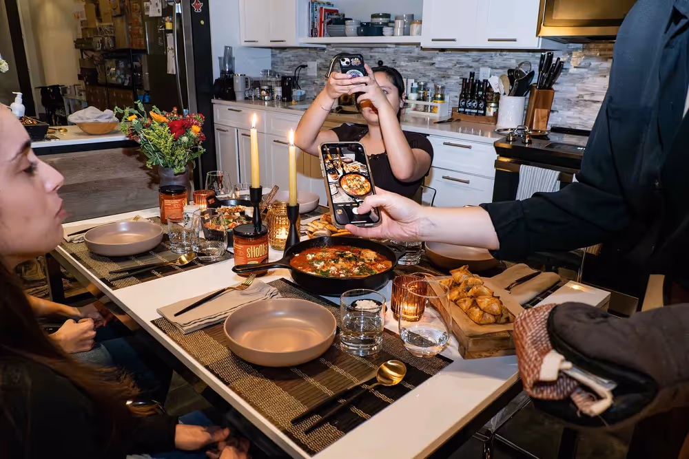 People gathered at a kitchen island with plated dishes and drinks, lifestyle photography by Photos by Lars.