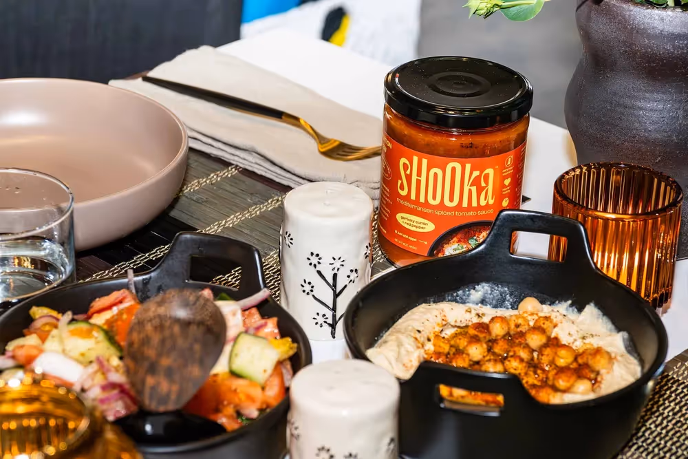Shooka sauce jar on dinner table with plated food and candles, lifestyle photography by Photos by Lars.