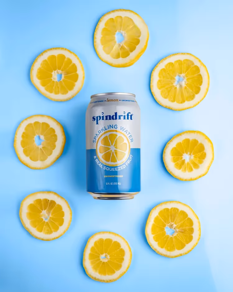 Spindrift Lemon sparkling water can framed by lemon slices on blue background, beverage photography by Photos by Lars.