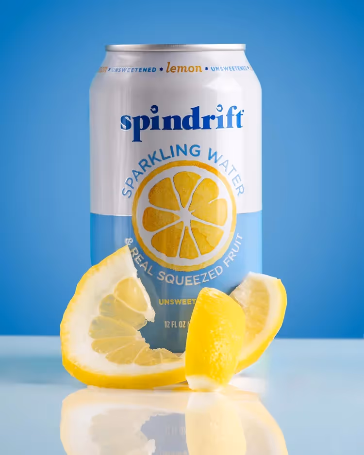 Spindrift Lemon sparkling water can with lemon wedges on reflective surface, product photography by Photos by Lars.