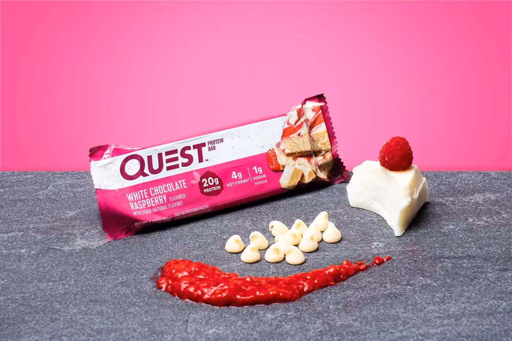 Quest bar with raspberry smear and white chocolate pieces on dark stone, food product photography by Photos by Lars.