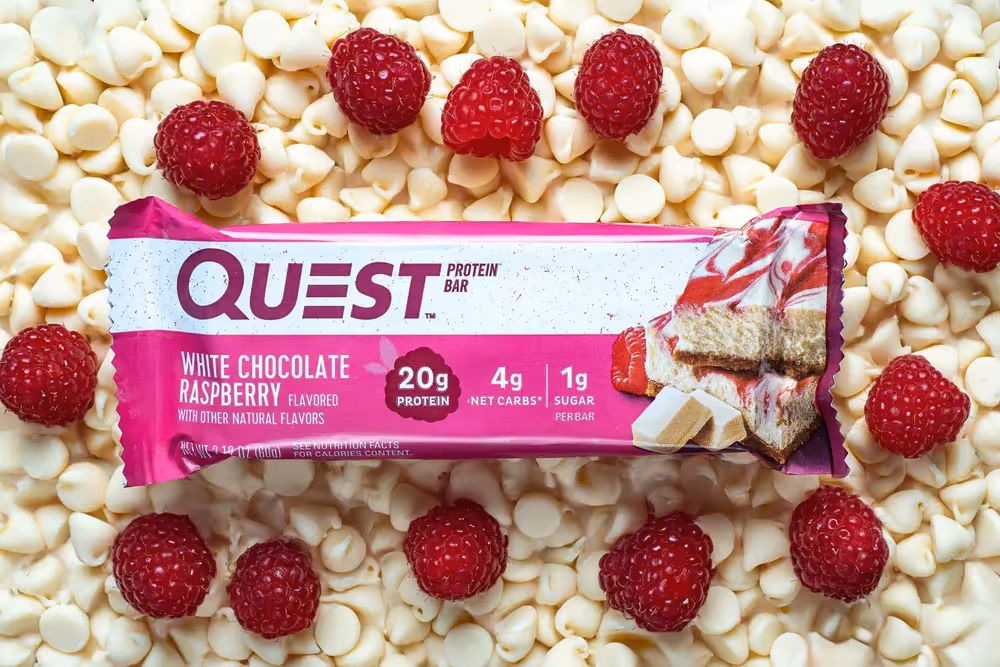 Quest White Chocolate Raspberry bar on bed of white chips with raspberries, food photography by Photos by Lars.