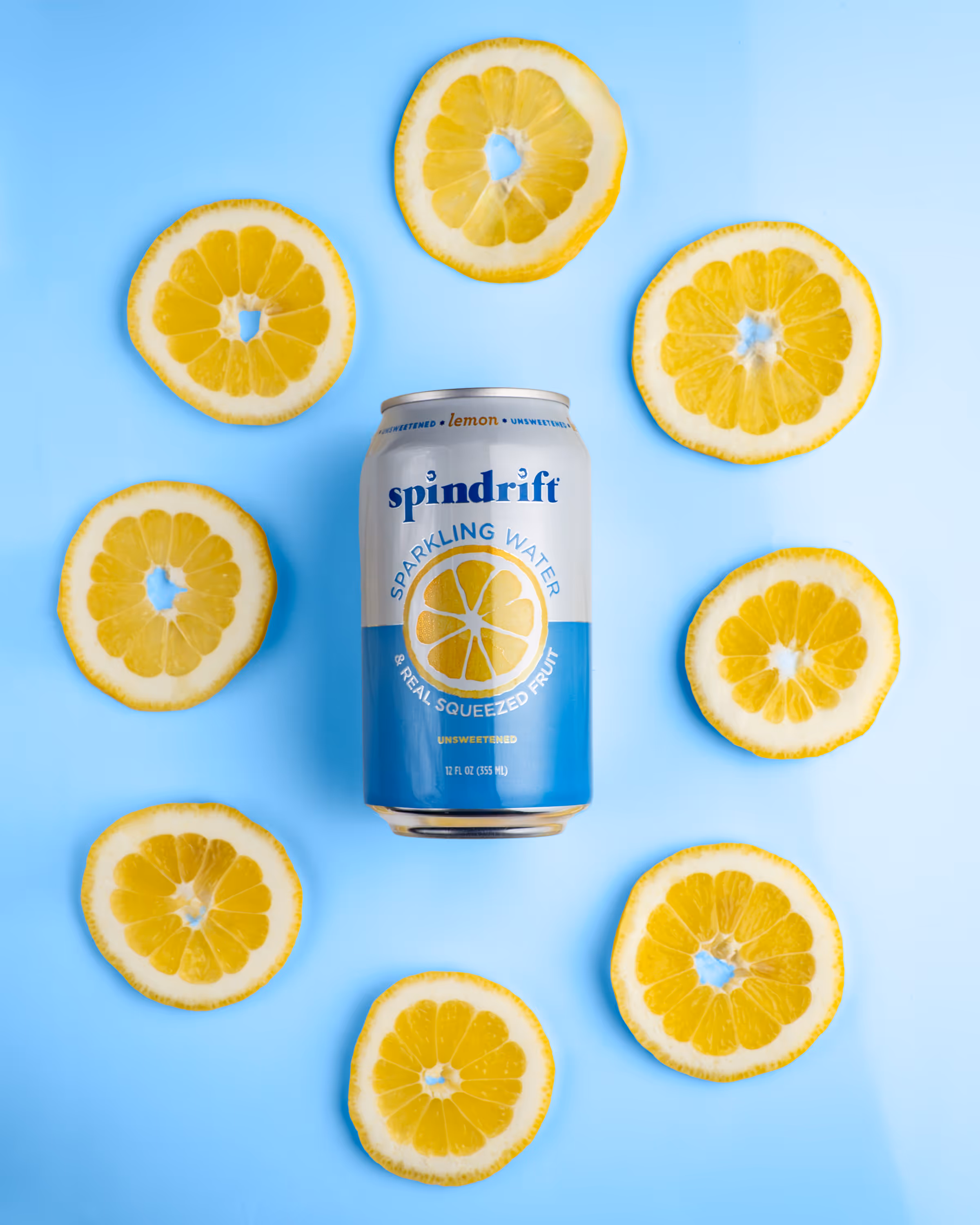 Spindrift lemon can surrounded by sliced lemons on light blue background, beverage photography Photos by Lars.