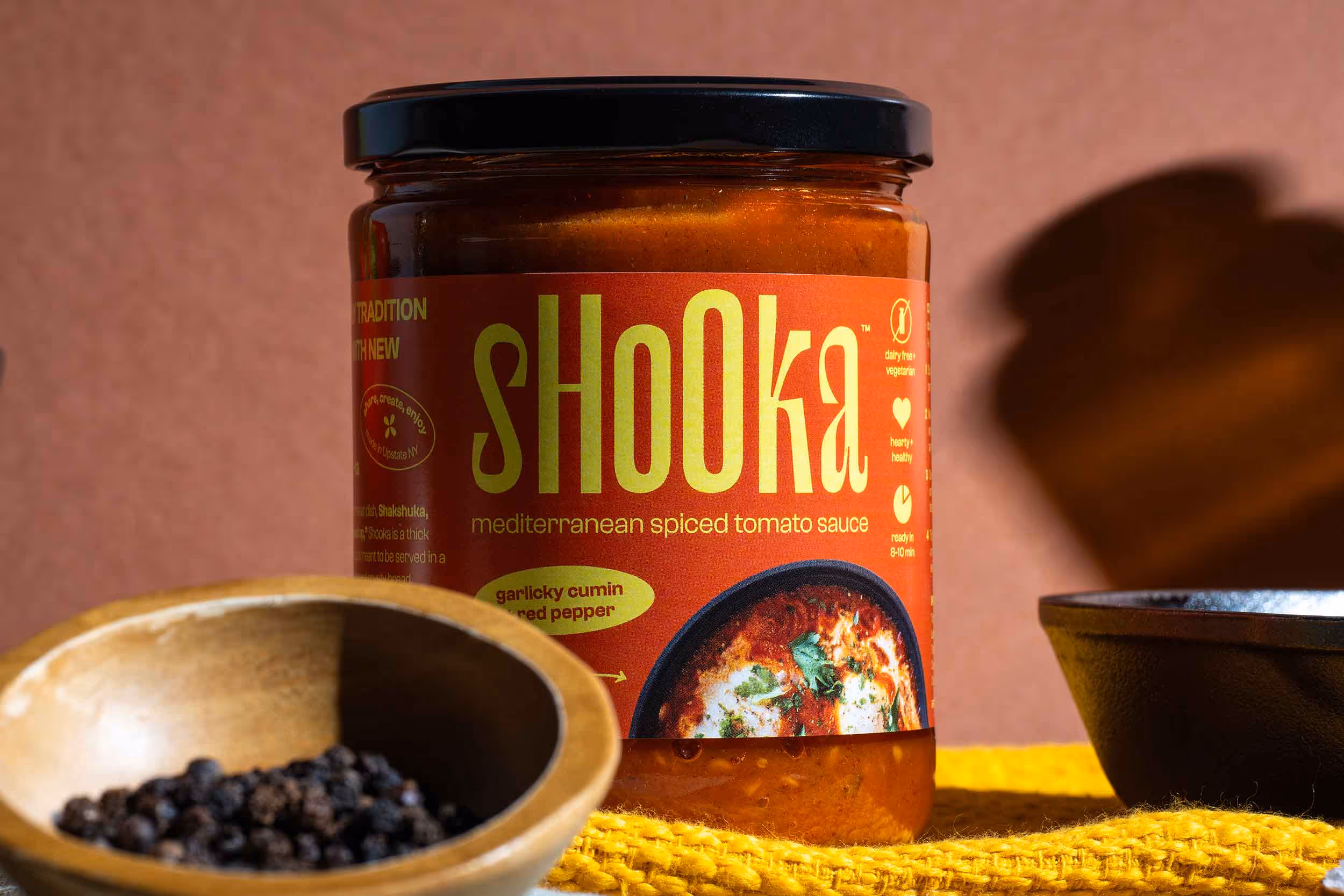 Shooka jar on yellow cloth with bowls of spices in foreground, food photography by Photos by Lars.