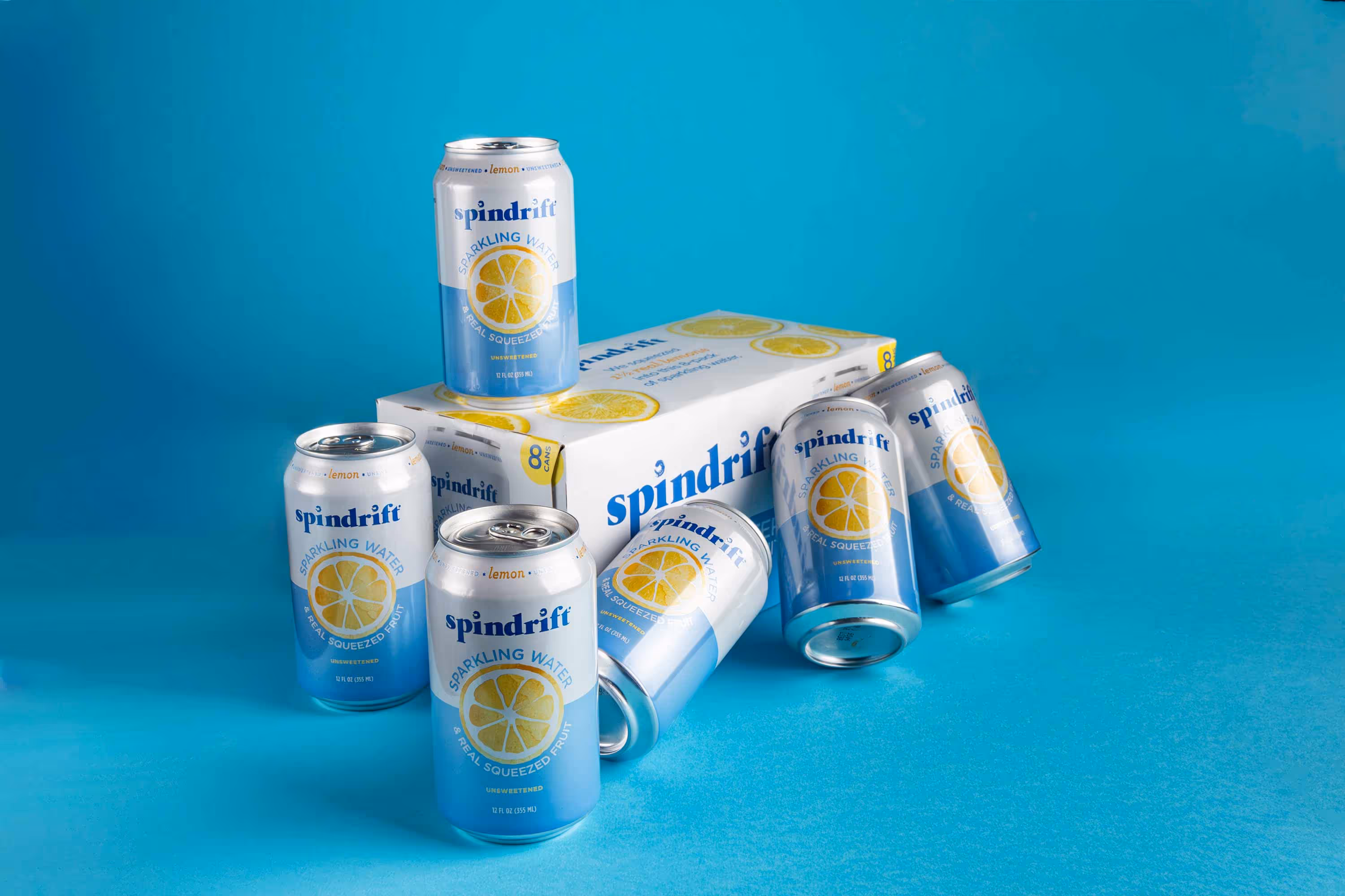 Spindrift lemon sparkling water cans stacked on blue surface, CPG product photo by Photos by Lars.