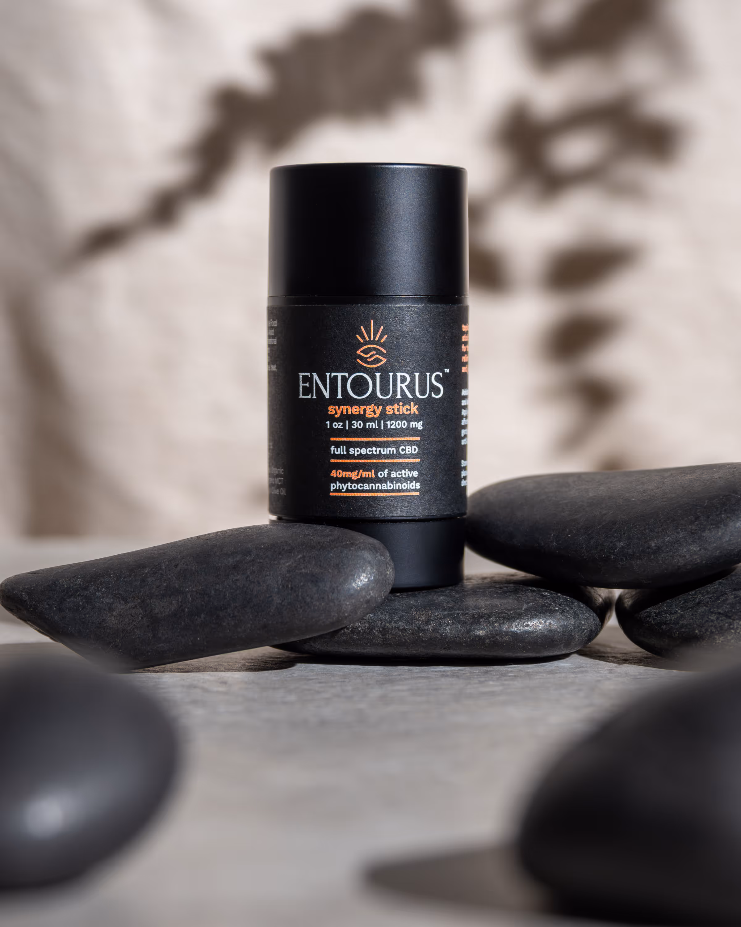 Entourus black jar on stacked smooth stones with soft neutral background, skincare product photography Photos by Lars