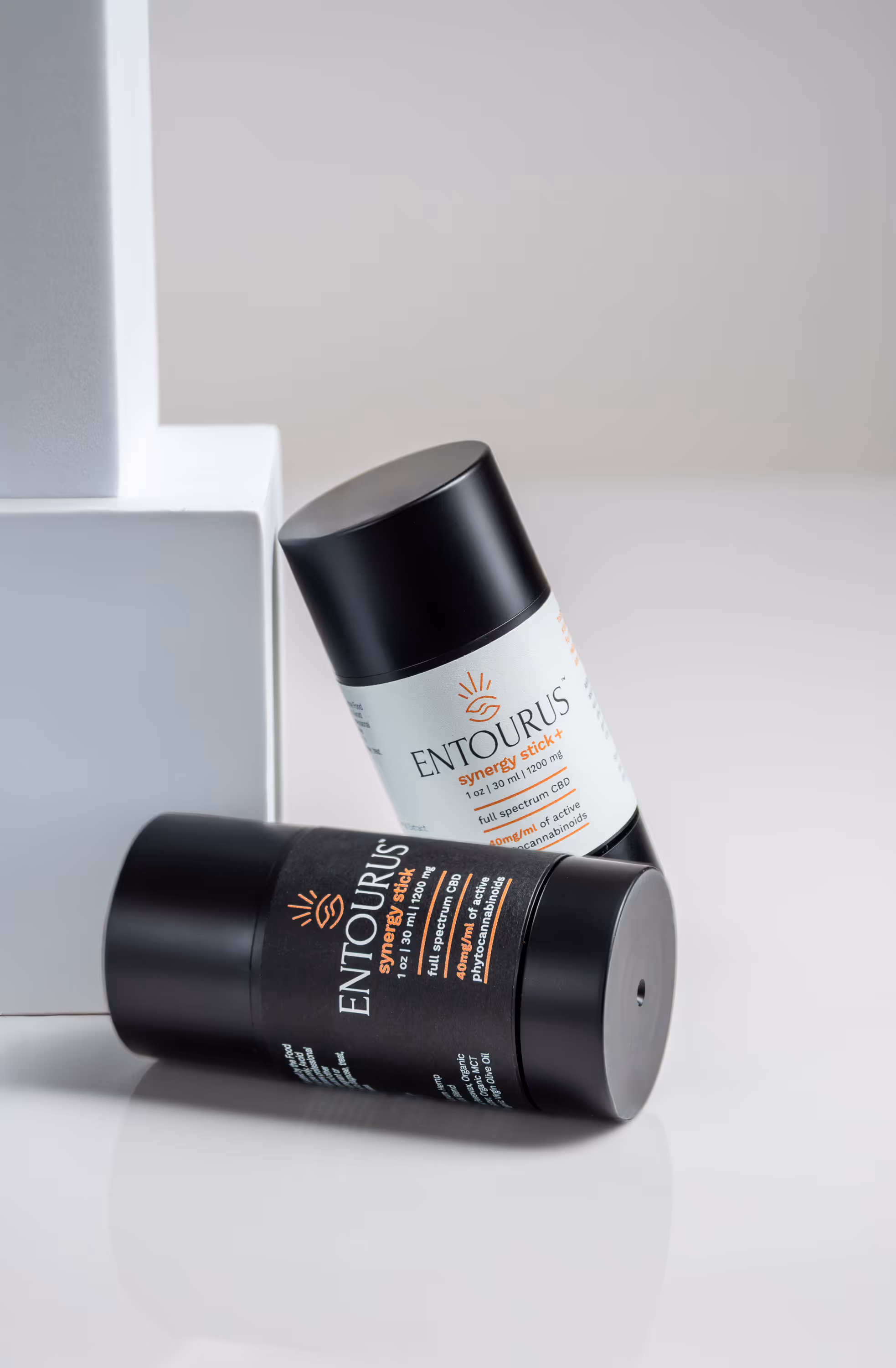 Entourus black jar lying on white surface with lid beside it, product photography Photos by Lars