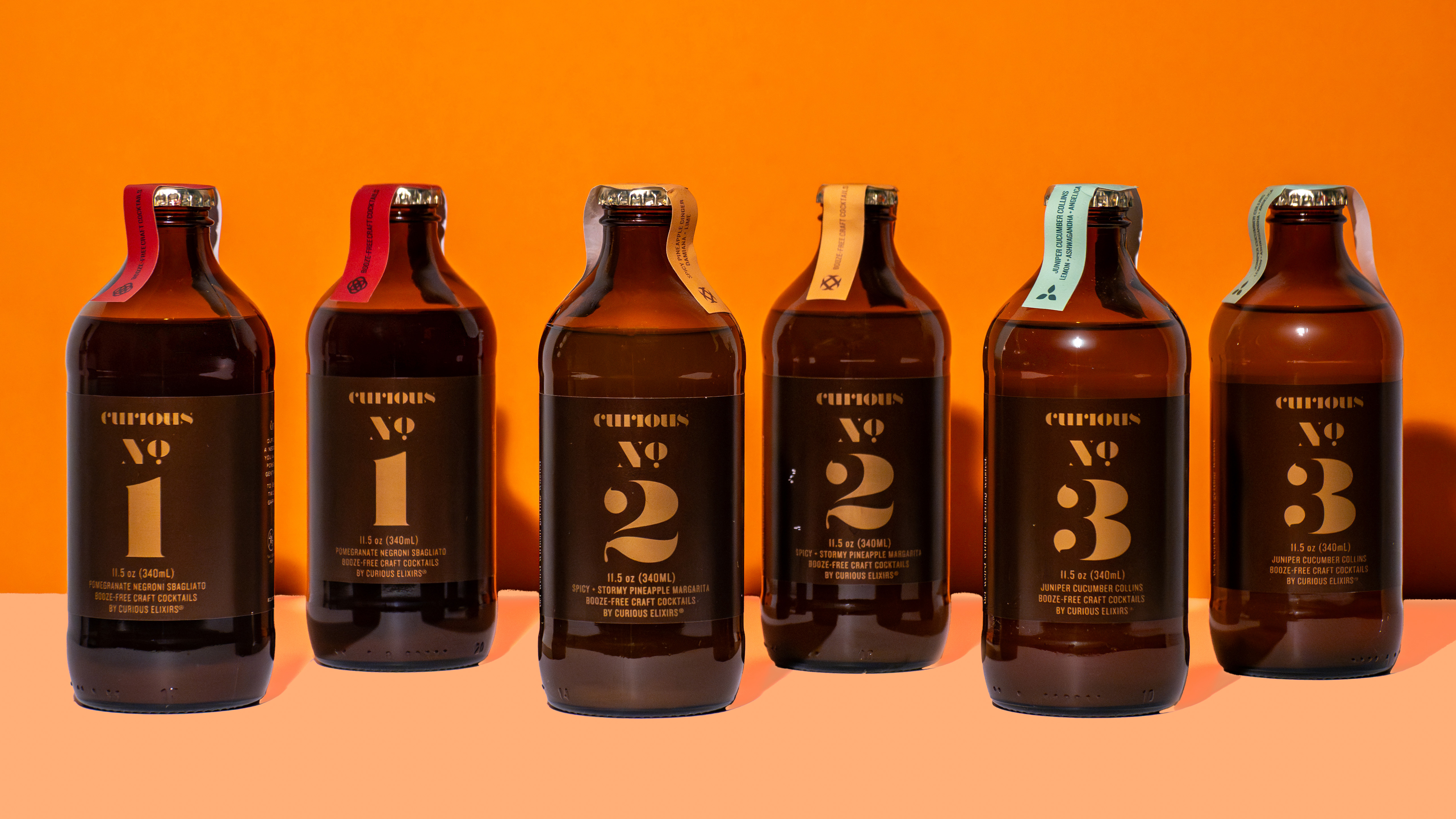 Row of dark glass bottles lined up on orange background, CPG product photo by Photos by Lars.