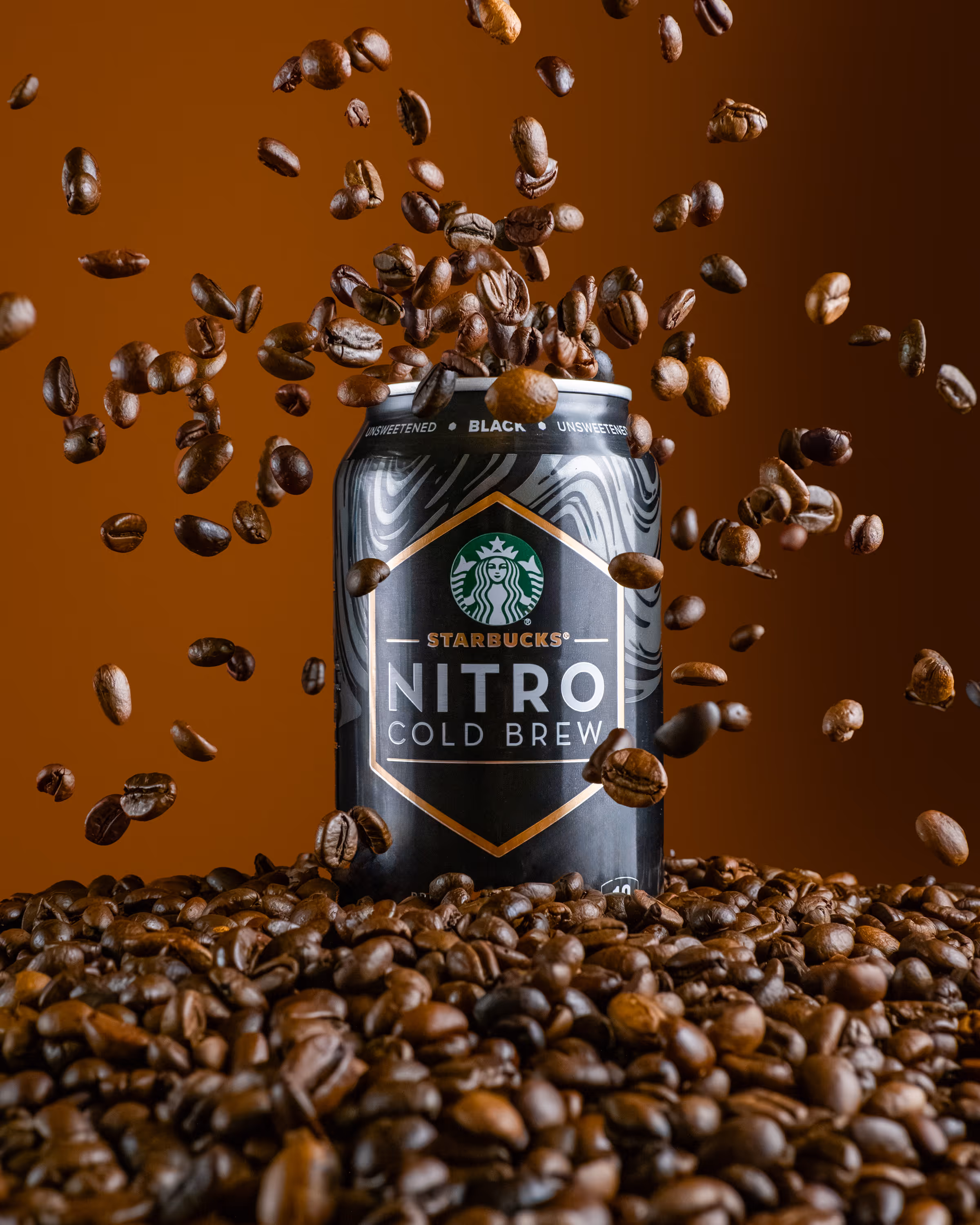 Starbucks Nitro Cold Brew can surrounded by coffee beans with beans falling, food photography, Photos by Lars.