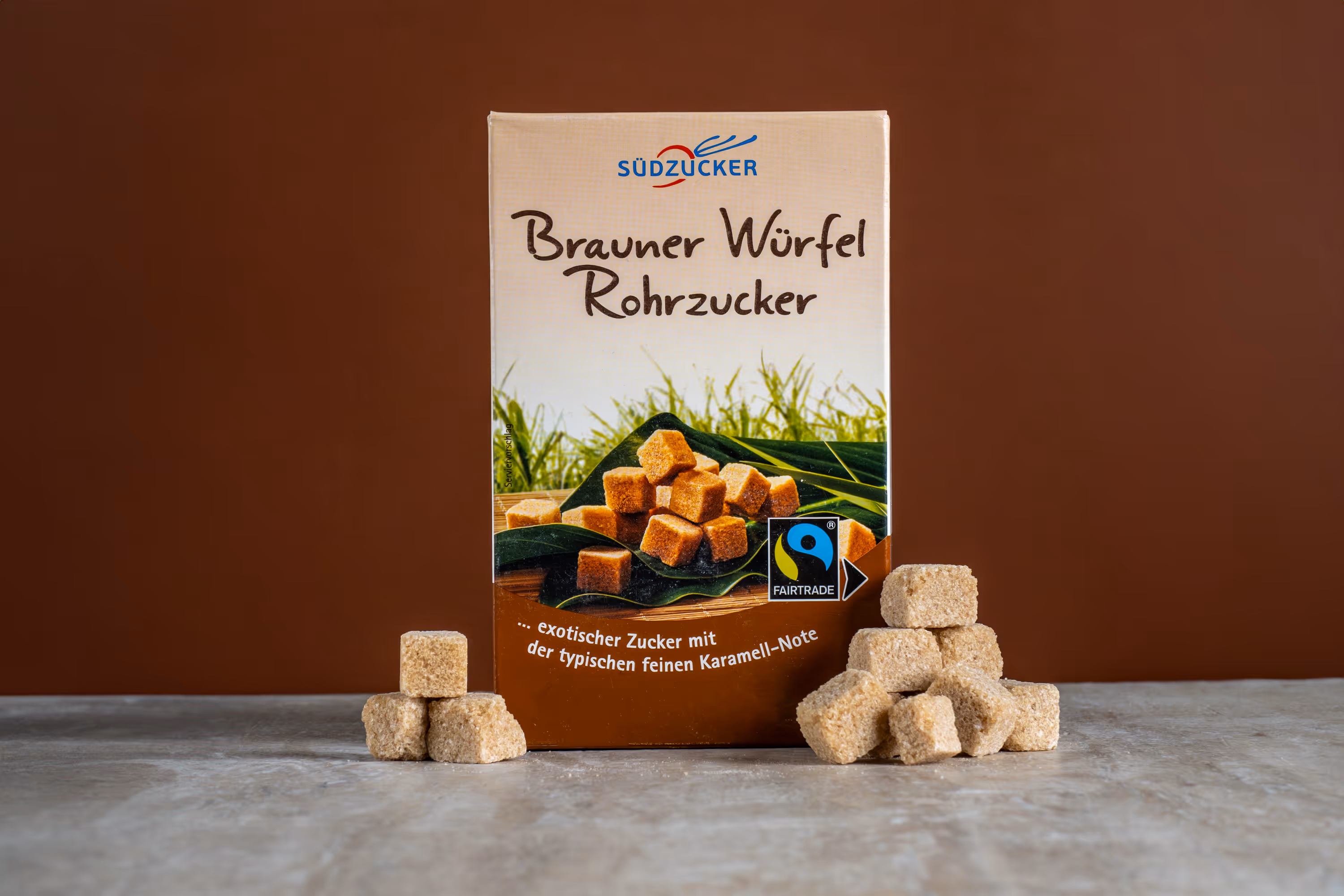 Südzucker “Brauner Würfel Rohrzucker” box with brown sugar cubes on stone surface, food product photo, Photos by Lars.