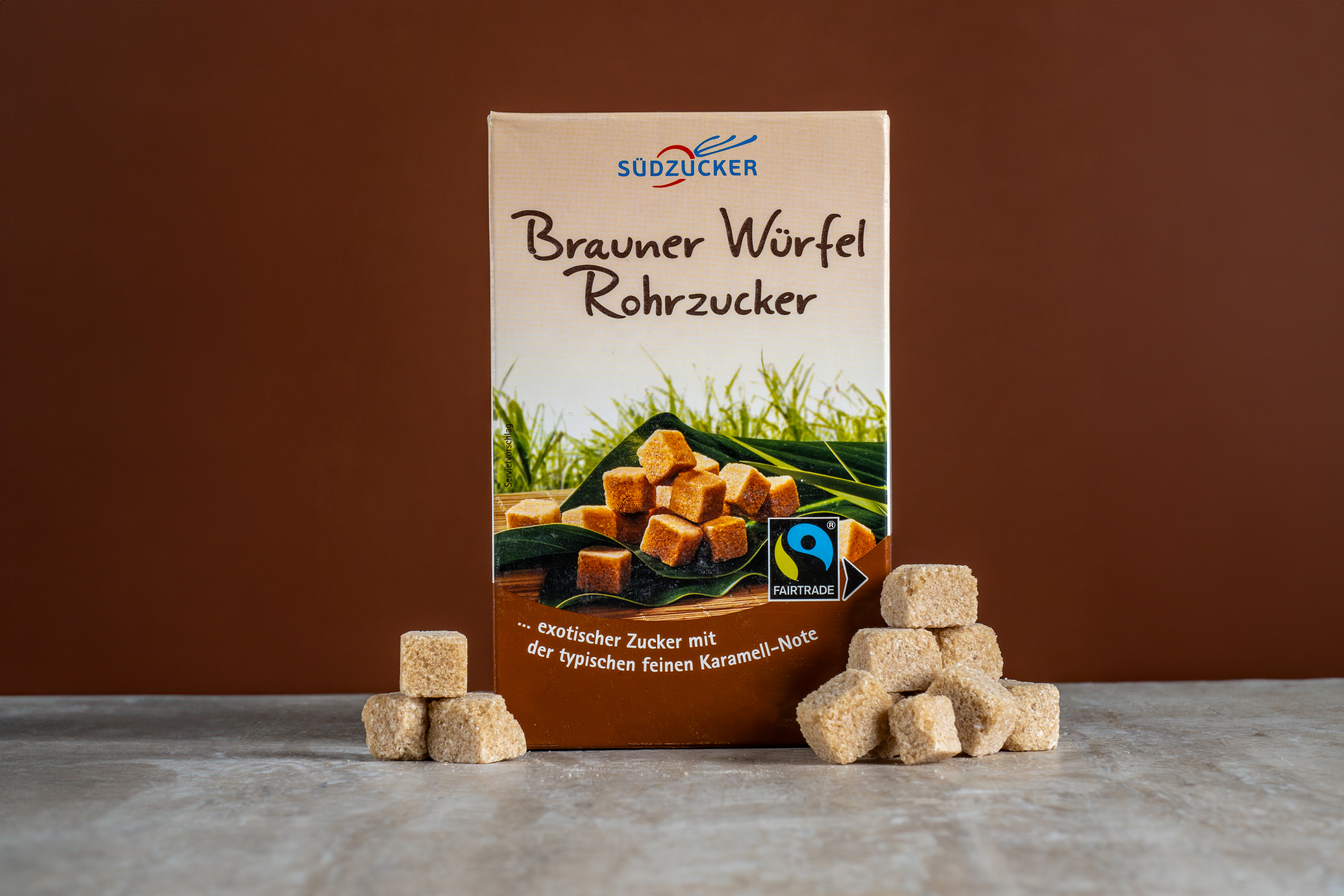 Südzucker “Brauner Würfel Rohrzucker” box with brown sugar cubes on stone surface, food product photo, Photos by Lars.