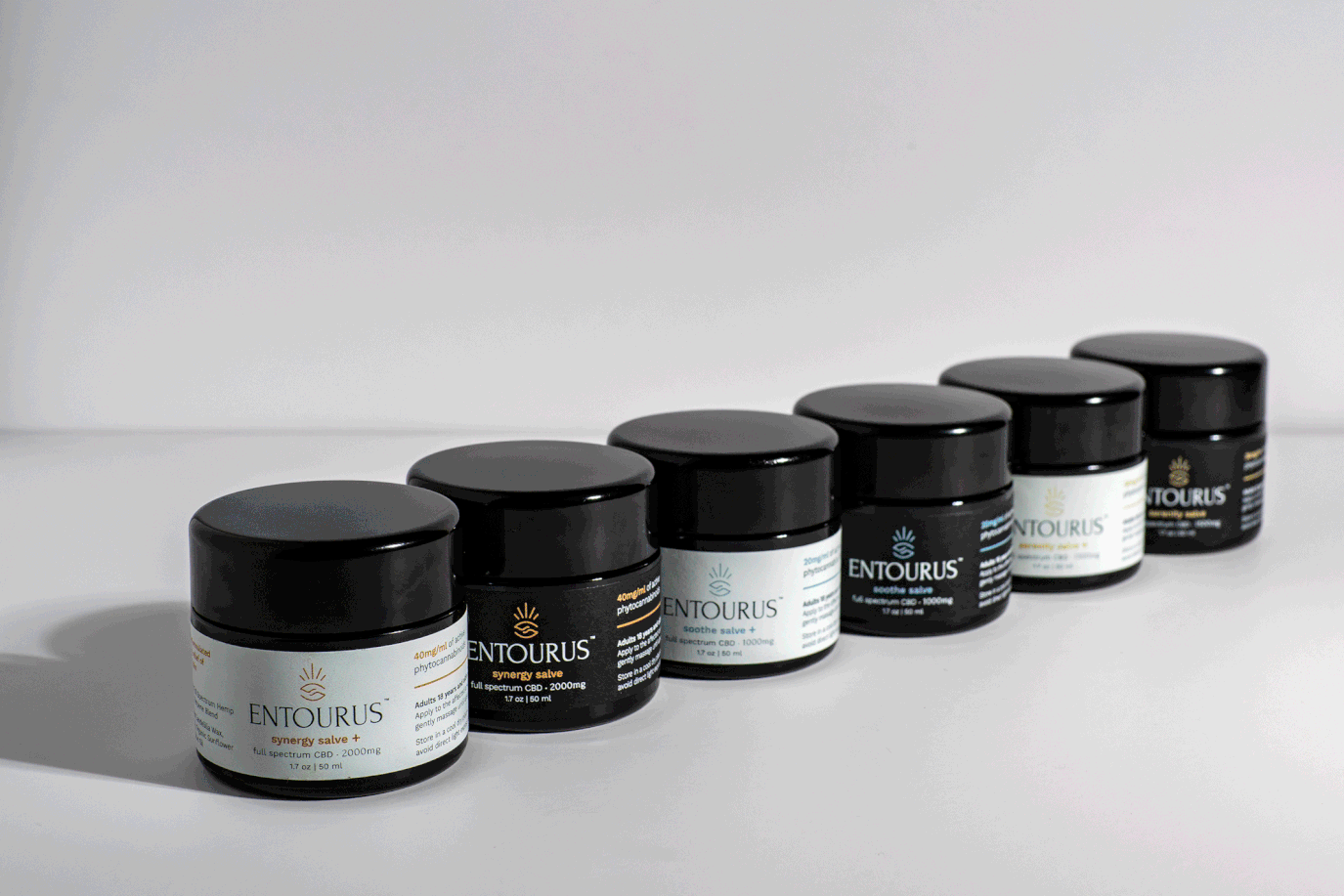 Row of Entourus jars with black-and-white labels on a white surface, Photos by Lars product stop motion.
