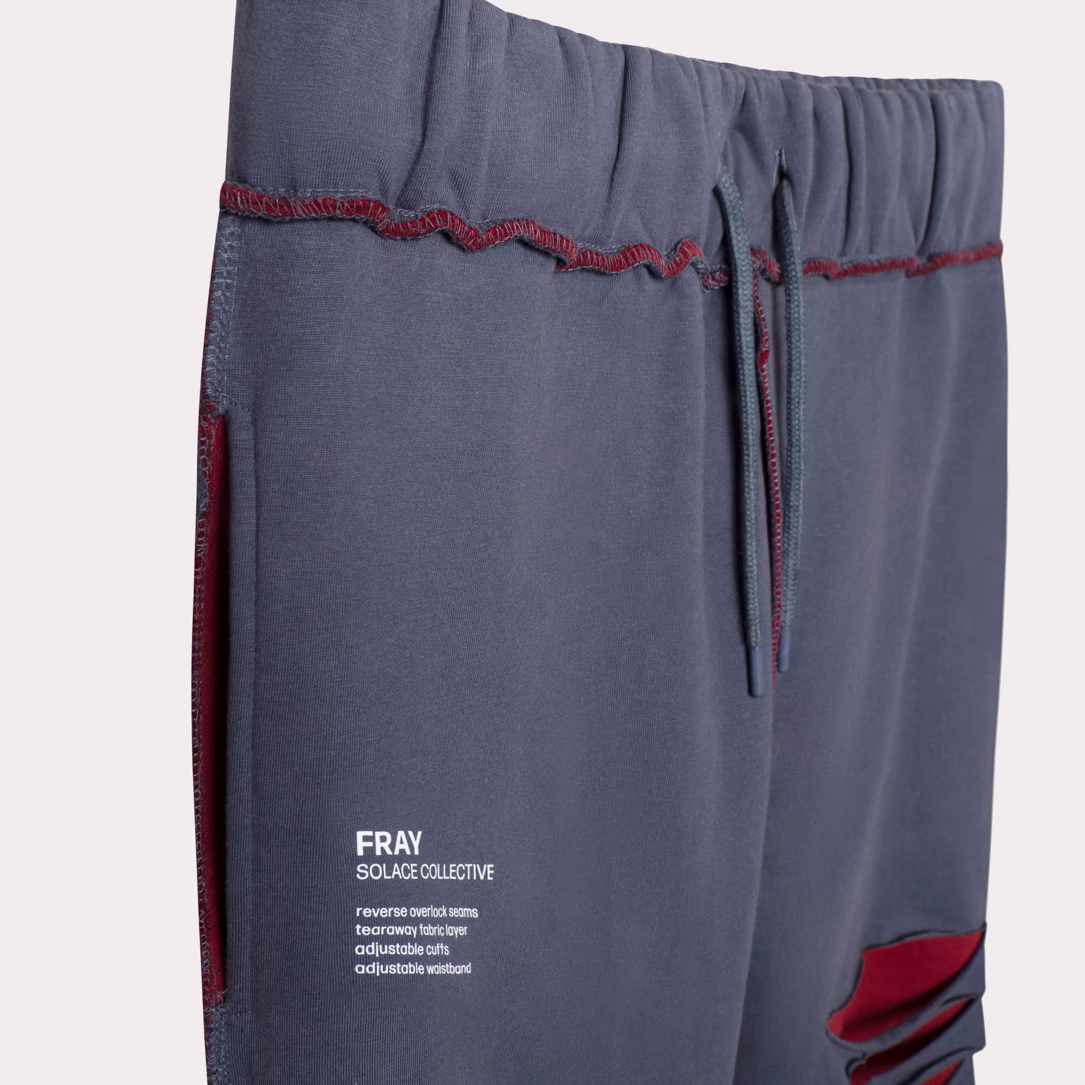 Blue SOLACE sweatpants waistband and pocket detail with red stitching, apparel product photography by Photos by Lars.