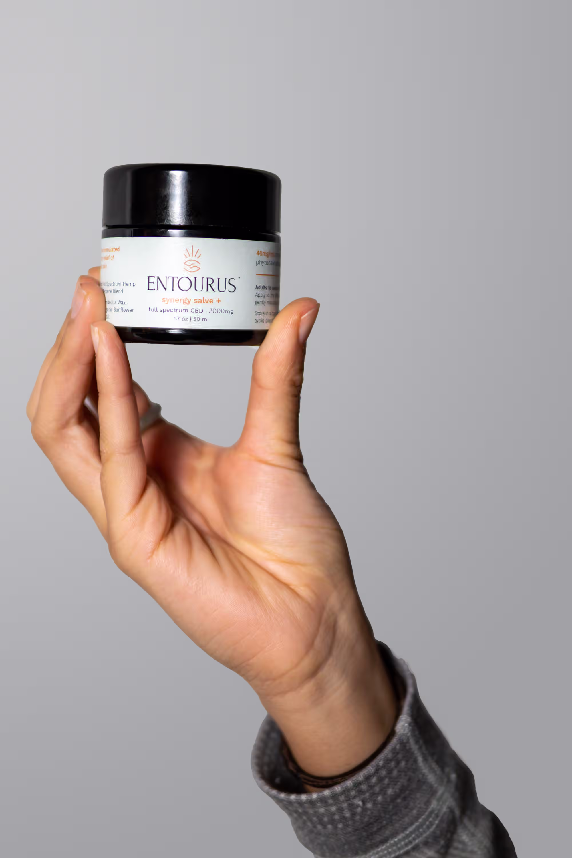 Hand holding Entourus Synergy Salve jar showing product scale for Amazon secondary image slot