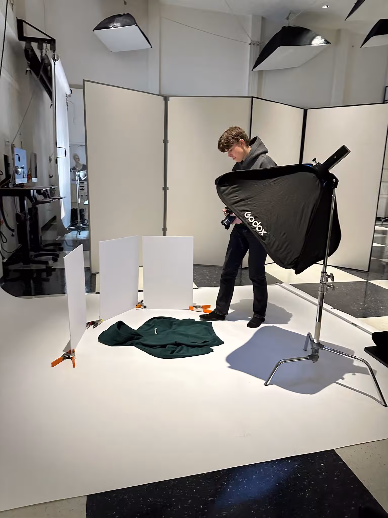 Photographer setting up a product shoot on a white sweep with Godox softbox and V-flat bounce cards at Photos by Lars studio