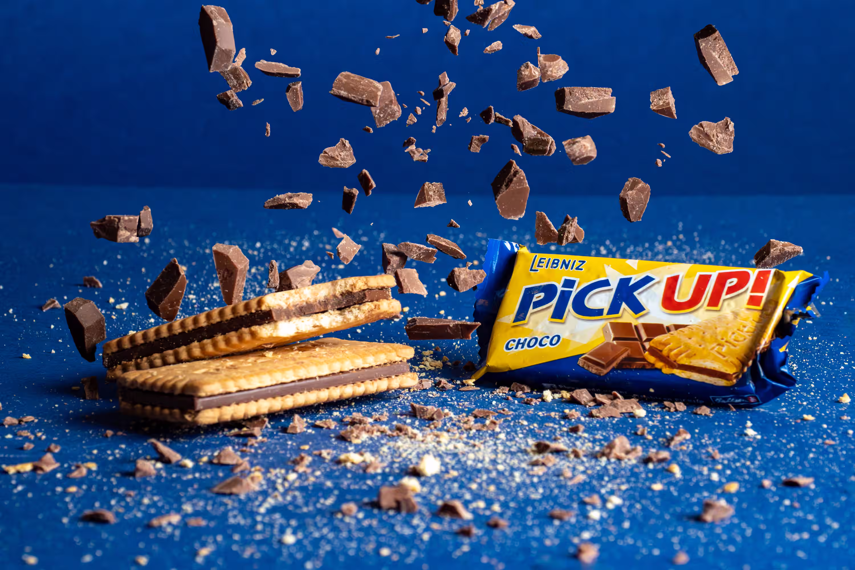 Leibniz Pick Up Choco biscuit with chocolate chunks exploding upward against a blue background in a motion product photograph