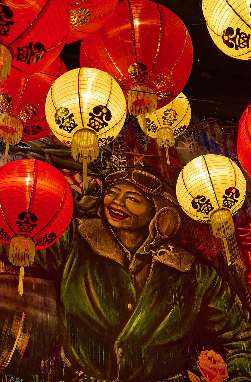 Hazel Ying private dining room at The Malarkey in Portland, designed by Tricorn Black, featuring a custom mural of Hazel Ying Lee and dramatic red and gold lantern lighting.