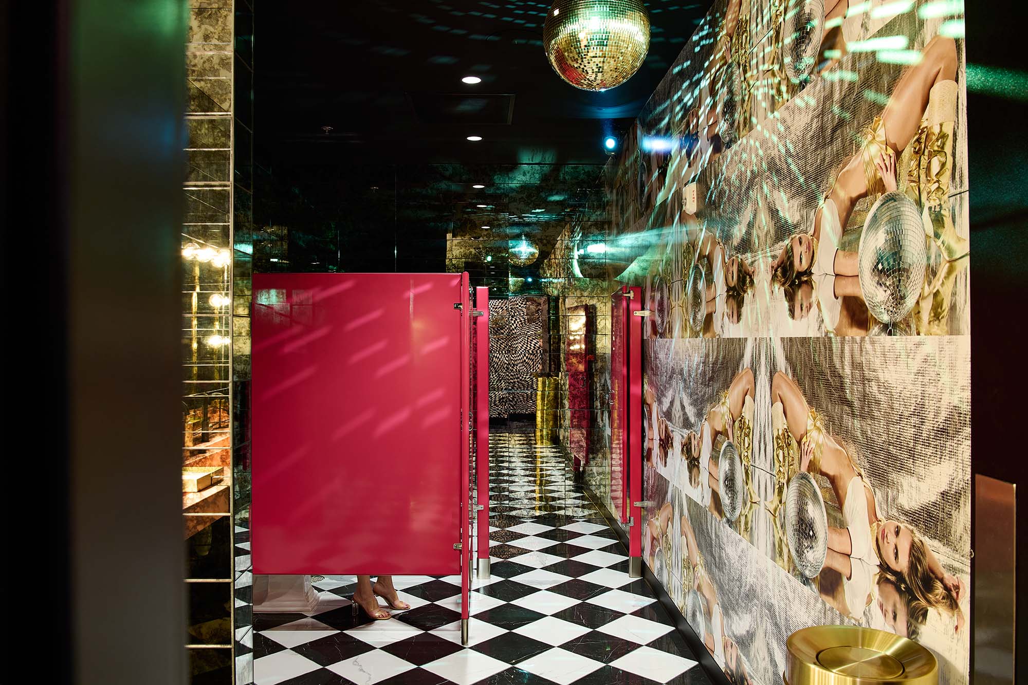 Restaurant bathroom at The Malarkey in Portland, designed by Tricorn Black, featuring mirrored walls, black-and-white checkerboard flooring, hot pink stalls and disco ball details.