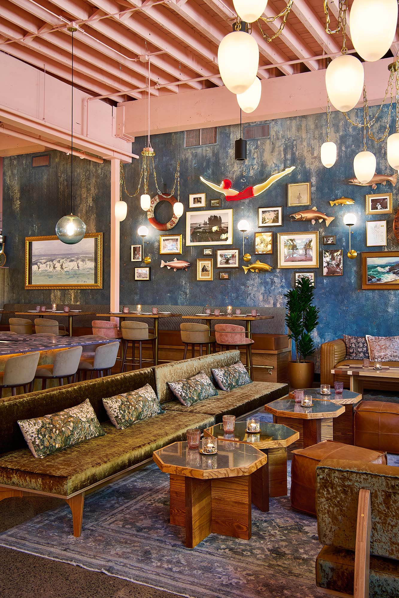 Lounge at The Malarkey in Portland, designed by Tricorn Black, featuring a neon sign of diving girl at Jantzen beach, layered vintage artwork, fish sculptures, sculptural pendant lighting and plush lounge seating.