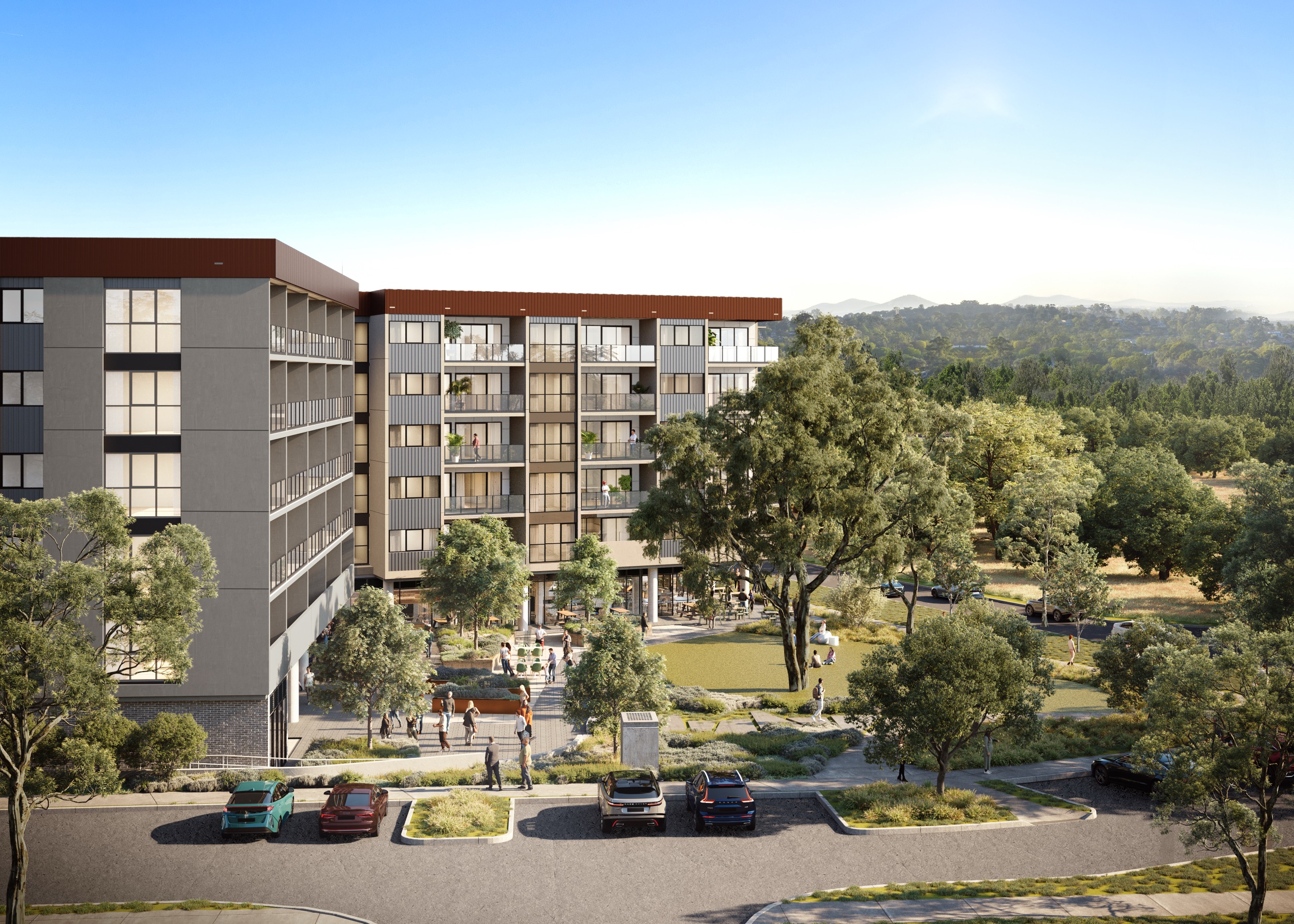 Modern apartment complex with balconies overlooking a green courtyard with walking paths and people, surrounded by trees and parked cars.