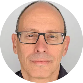 Close-up portrait of a middle-aged man with short hair, glasses, and a neutral expression.