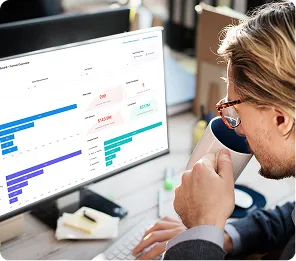 Person with glasses drinking coffee and analyzing colorful bar charts and statistics on a computer screen.