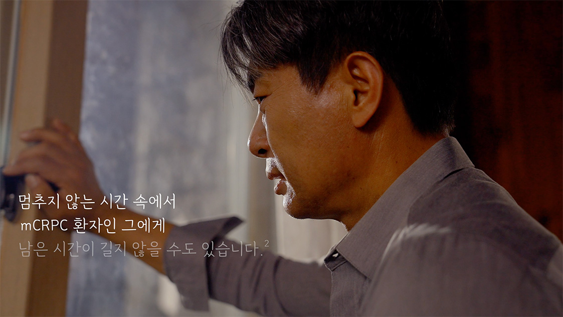 Side view of a middle-aged man in a gray shirt touching glass or a window with a serious expression.