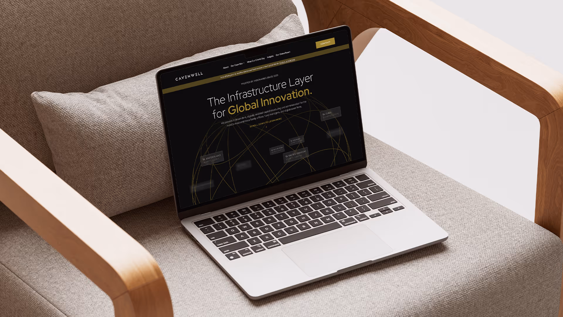 Open laptop resting on a gray fabric armchair with a website about global infrastructure innovation displayed on the screen.