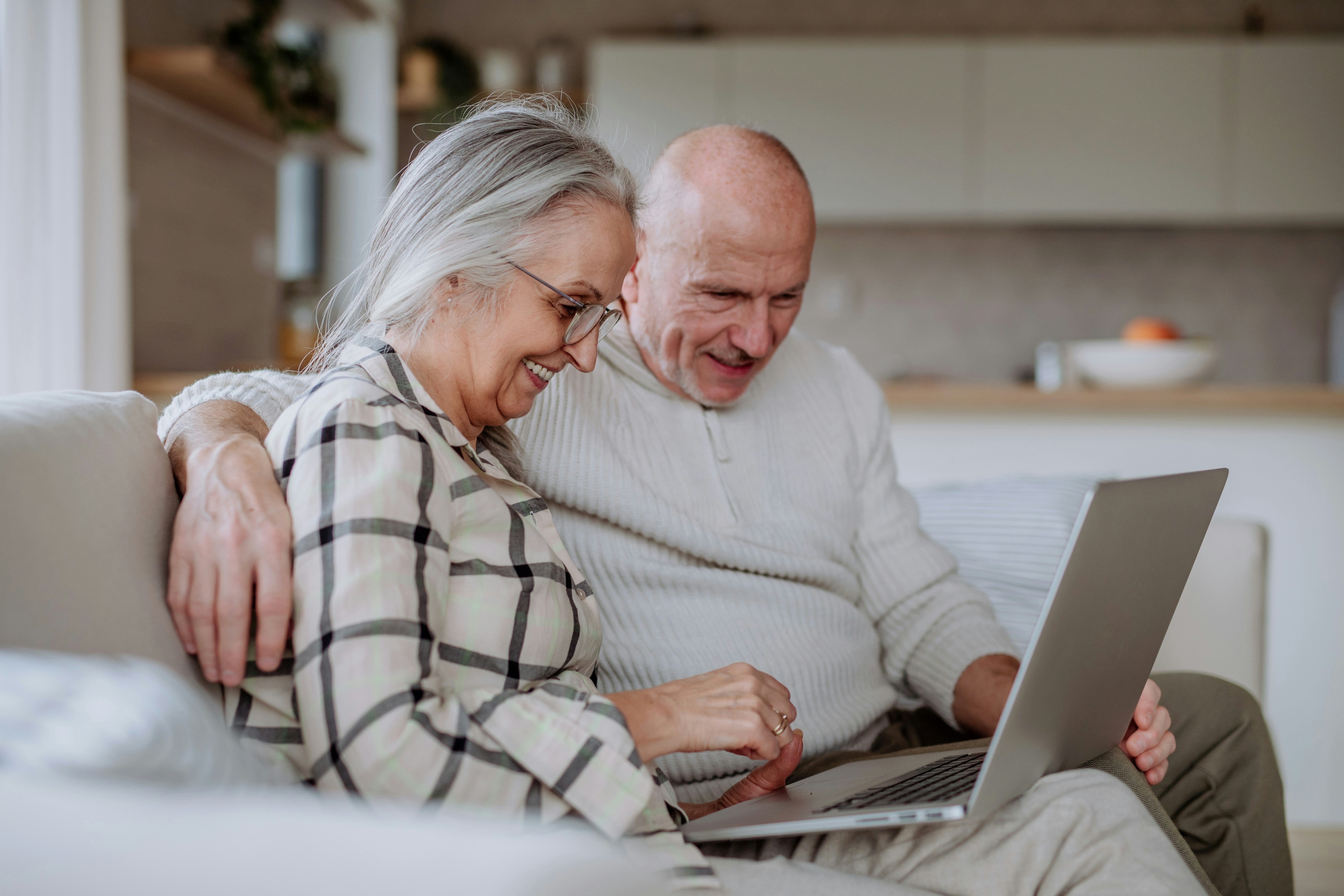 Un couple de seniors étudie un guide complet en ligne qui détaille le fonctionnement du crédit d'impôt immédiat pour l'aide à domicile