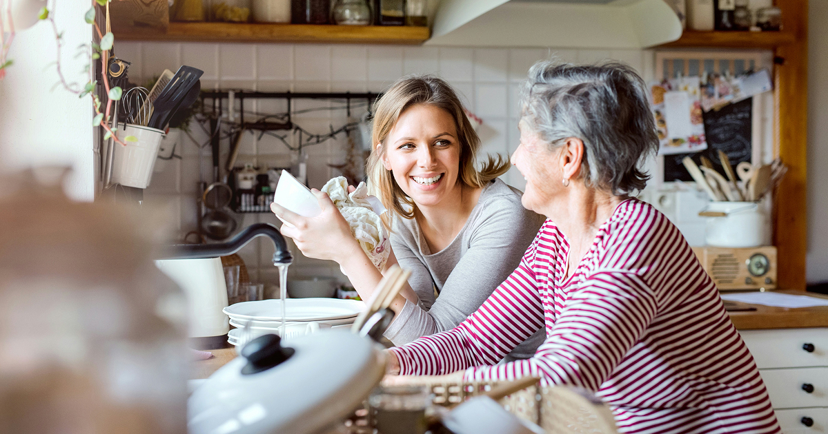 Aide à domicile partageant un moment de complicité avec une personne âgée dans une cuisine