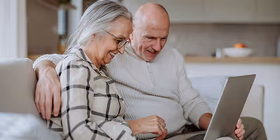 Un couple de seniors étudie un guide complet en ligne qui détaille le fonctionnement du crédit d'impôt immédiat pour l'aide à domicile