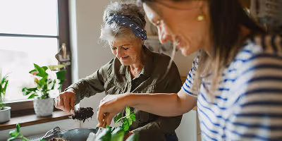 Une aide a domicile au début de sa reconversion professionnelle dans ce secteur partageant un moment de complicité avec une bénéficiaire dans sa cuisine
