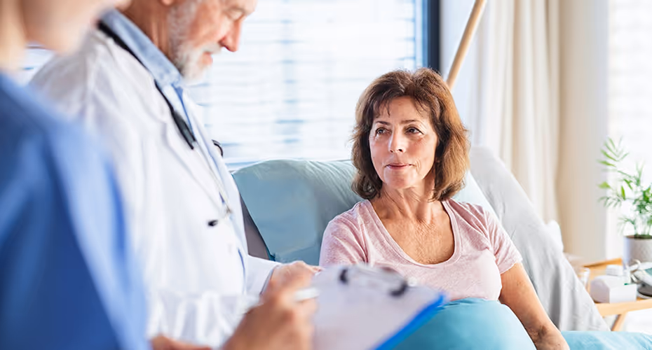 Équipe médico-sociale (médecin et infirmière) préparant le dossier d'aide ARDH CARSAT pour une patiente hospitalisée.