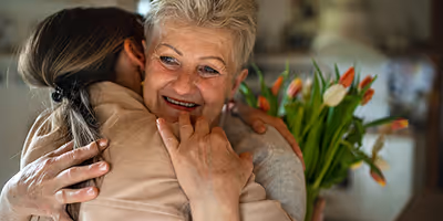 Femme senior souriante enlacée par une aide à domicile, illustrant la sérénité du CESU avec Provence Aide Services.