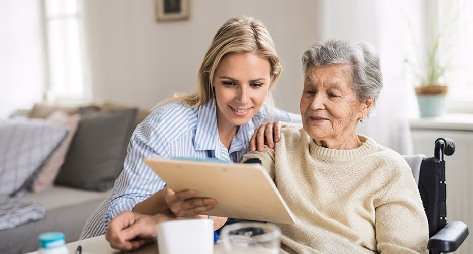 Une personne âgée et sa fille son entrain de chercher sur une tablette des informations pour embaucher une aide à domicile