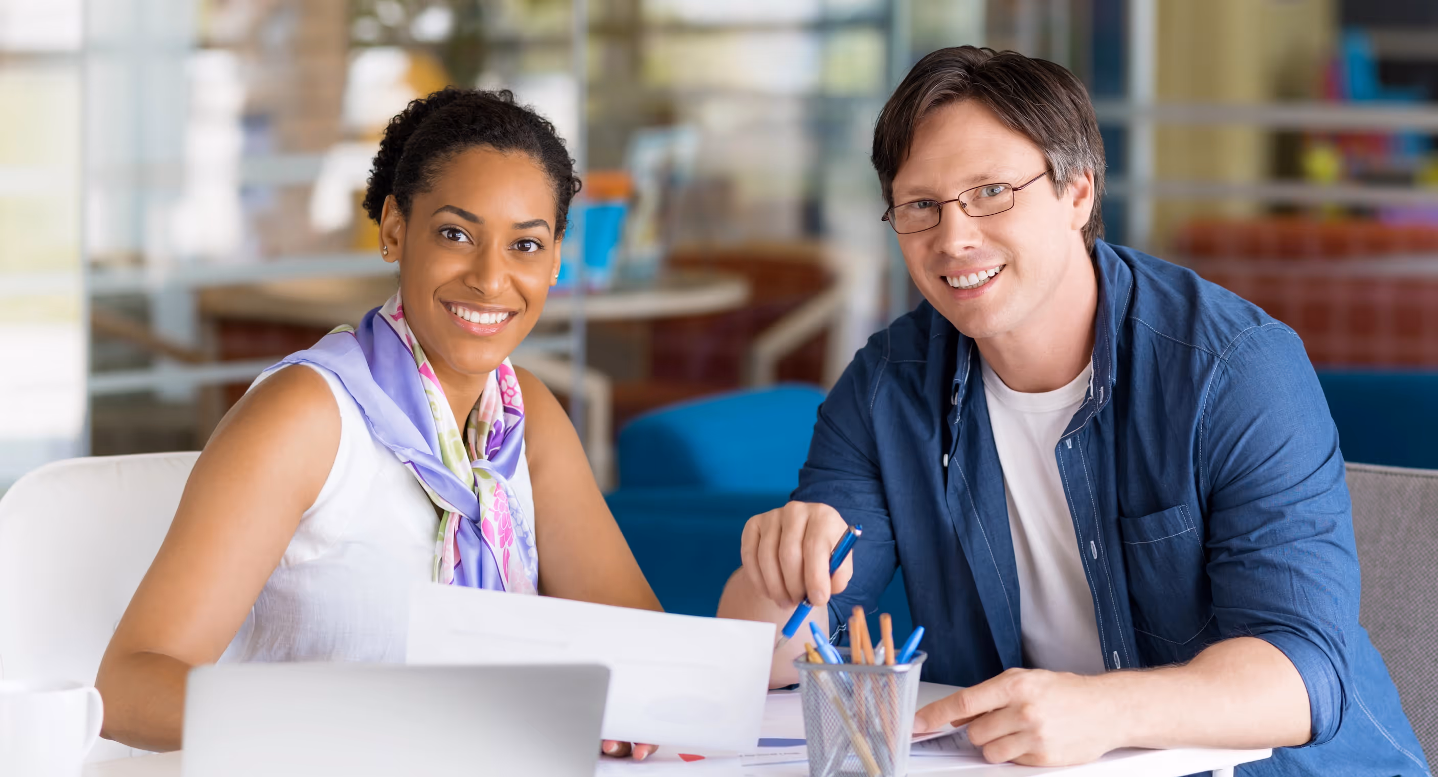 Coach and client smiling during a coaching session in a modern workspace.