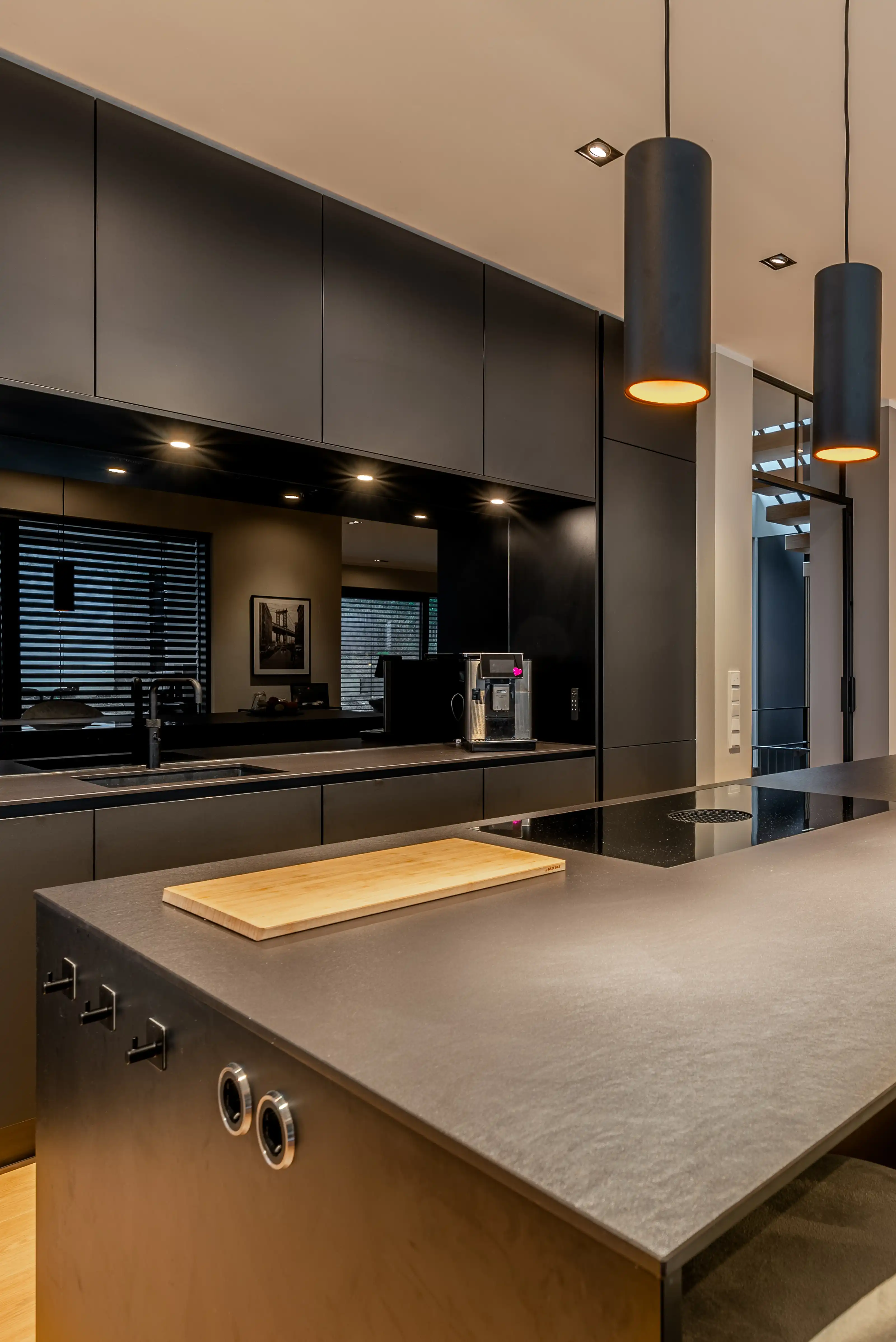 Moderne schwarze Küche mit Betonoptik-Arbeitsplatte, Kücheninsel und Pendelleuchten.