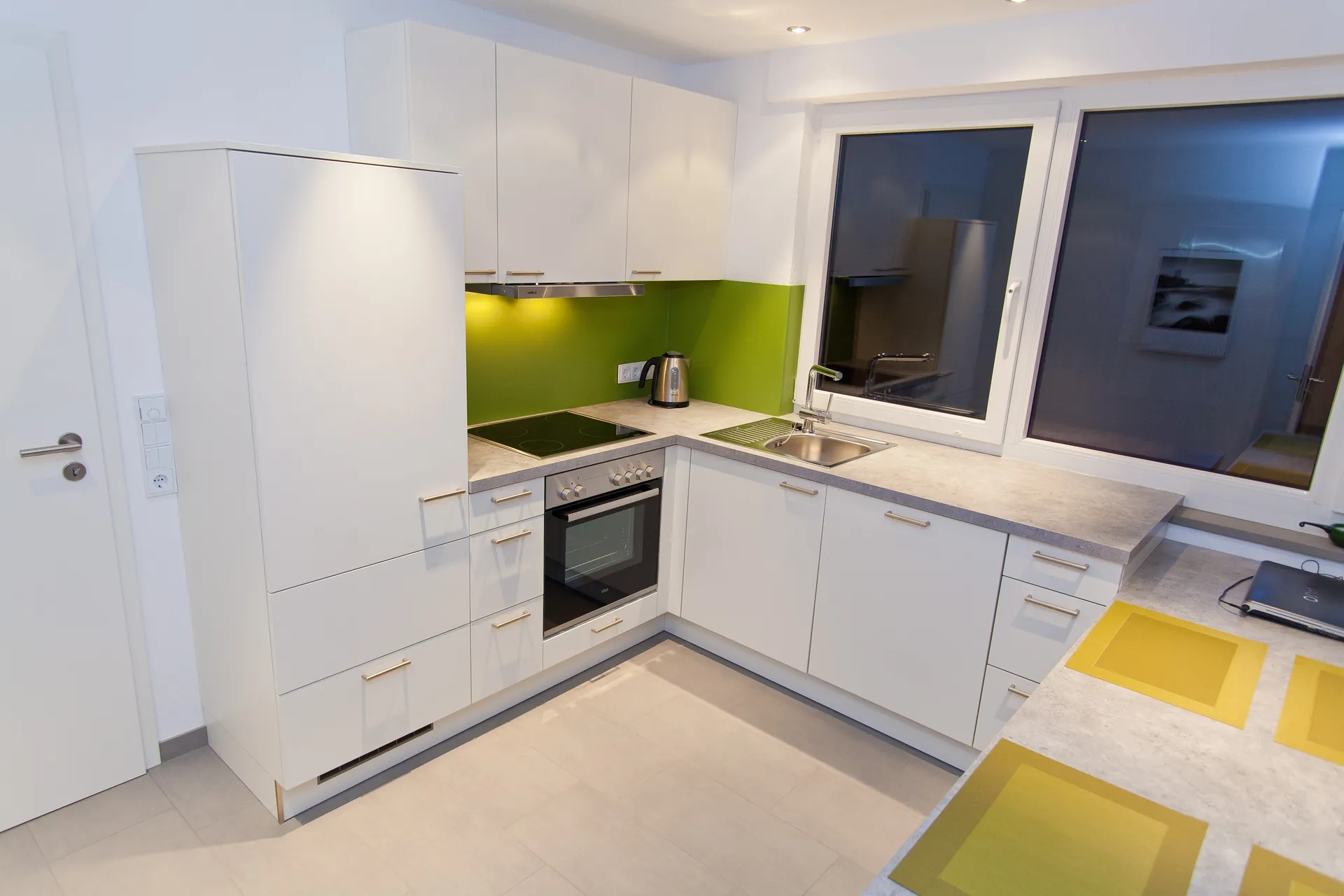 Designküche – Grifflose weiße Küche mit markanter Grauwacke-Arbeitsplatte