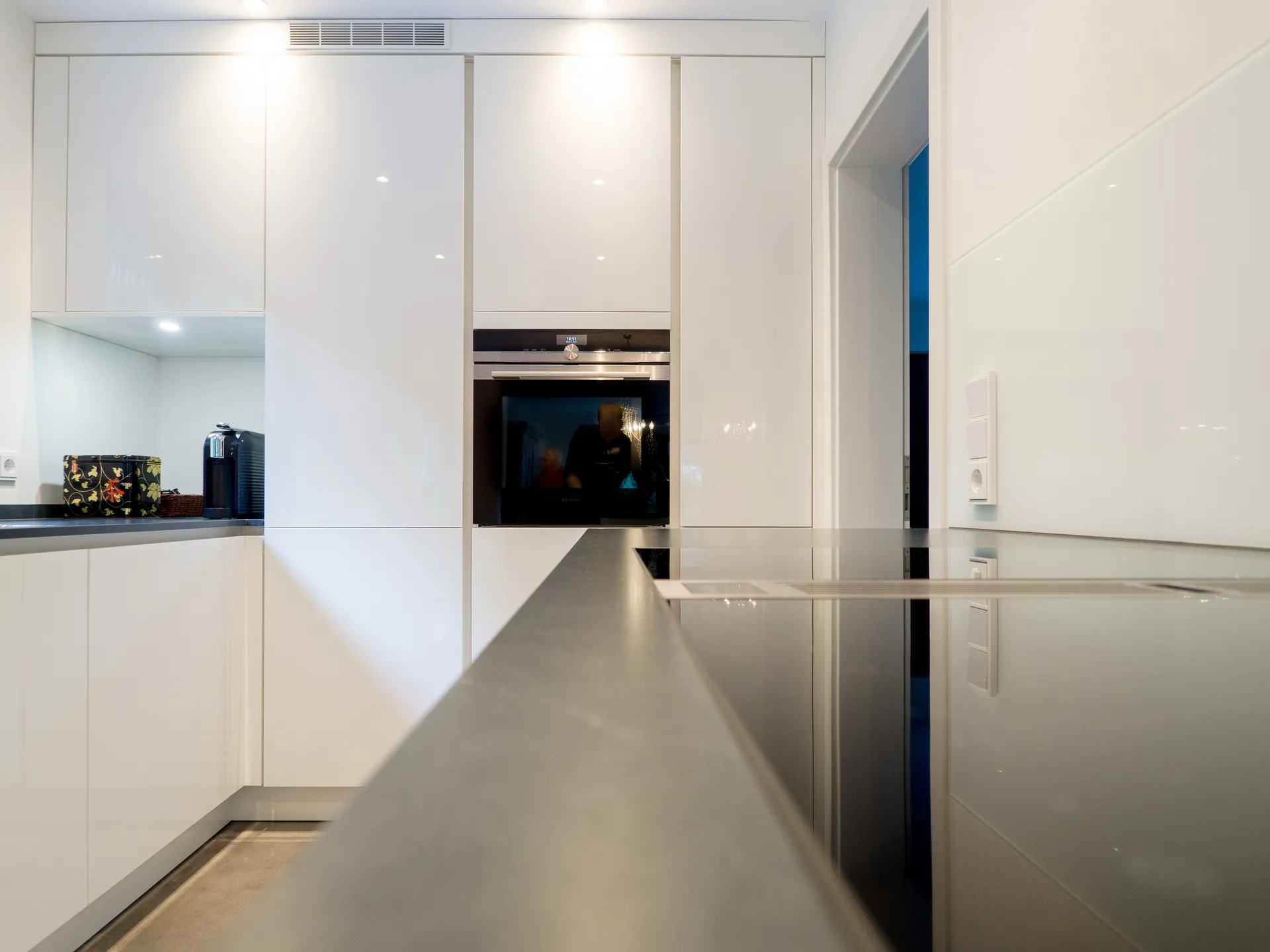 Designküche – Grifflose Hochglanz Küche in Weiß mit stilvoller Rückwand