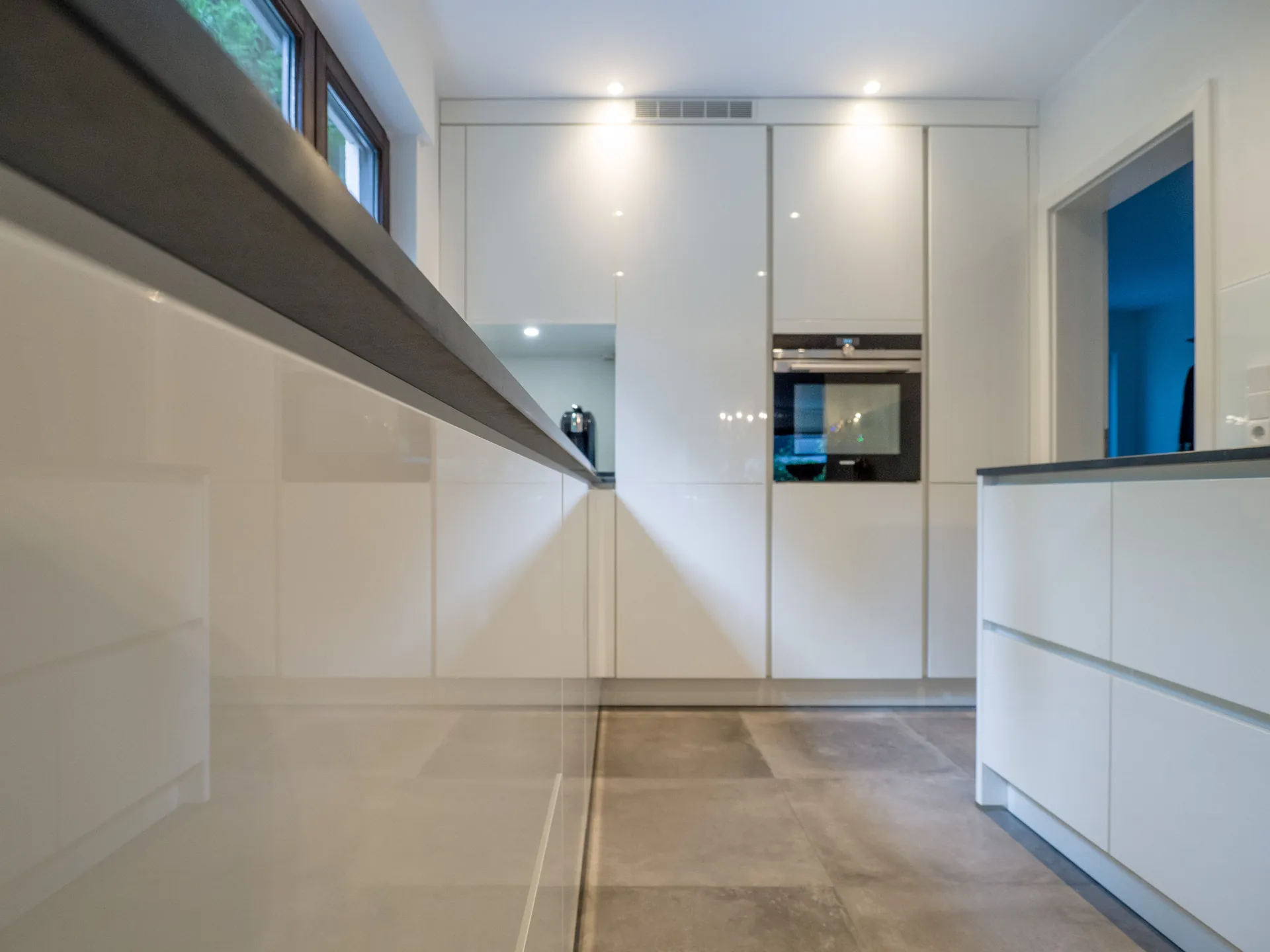 Designküche – Grifflose Hochglanz Küche in Weiß mit stilvoller Rückwand