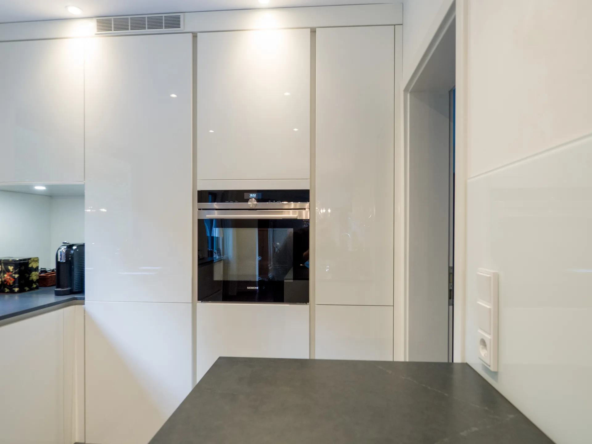 Designküche – Grifflose Hochglanz Küche in Weiß mit stilvoller Rückwand